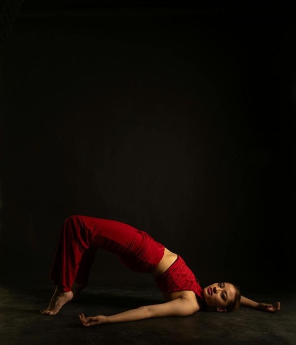 Woman performing a balanced yoga pose in a dark studio